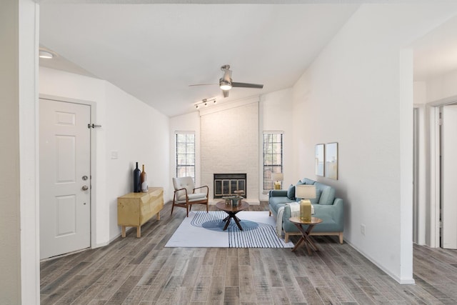 living area featuring ceiling fan, a stone fireplace, hardwood / wood-style floors, and lofted ceiling