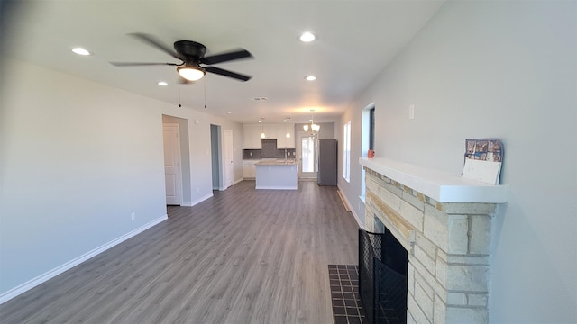 unfurnished living room featuring hardwood / wood-style flooring, a fireplace, and ceiling fan with notable chandelier