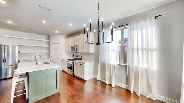 kitchen with appliances with stainless steel finishes, white cabinetry, decorative backsplash, sink, and a center island with sink