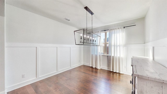 unfurnished dining area featuring dark hardwood / wood-style floors and a chandelier