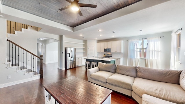 living room featuring a raised ceiling, sink, dark wood-type flooring, wooden ceiling, and ceiling fan with notable chandelier