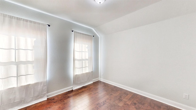 empty room with dark wood-type flooring and vaulted ceiling