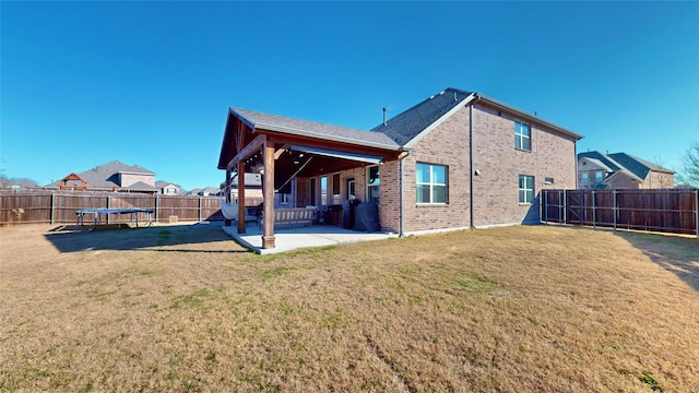 back of house with a yard, a patio, and a trampoline