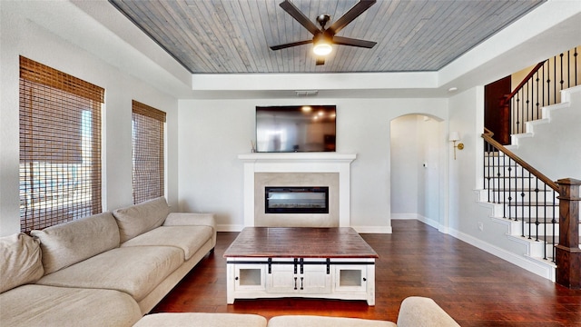 living room with ceiling fan, dark wood-type flooring, wooden ceiling, and a tray ceiling