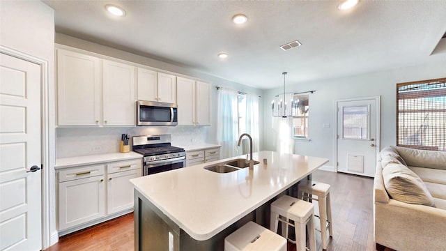 kitchen featuring sink, a center island with sink, white cabinetry, and appliances with stainless steel finishes