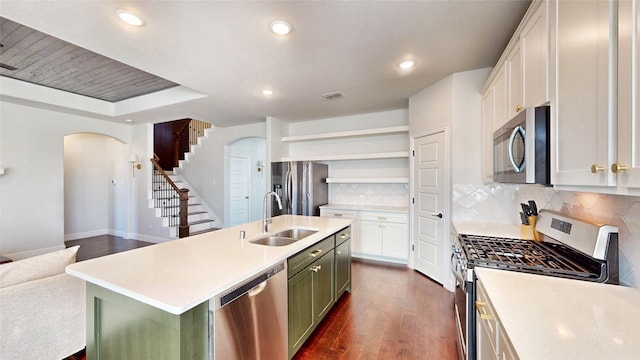 kitchen with dark hardwood / wood-style flooring, sink, appliances with stainless steel finishes, white cabinetry, and a center island with sink