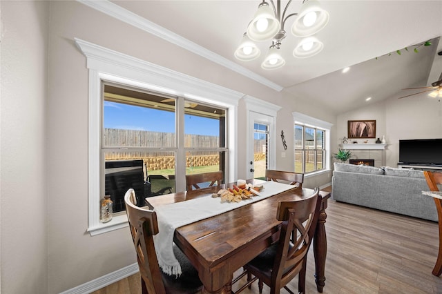 dining area with ceiling fan with notable chandelier, hardwood / wood-style floors, crown molding, and lofted ceiling