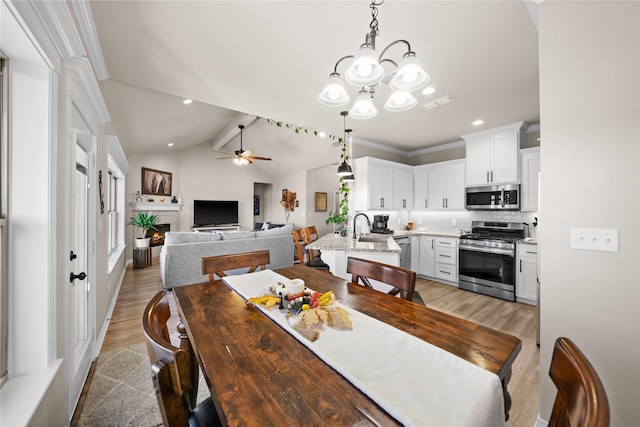 dining space with crown molding, light hardwood / wood-style flooring, sink, lofted ceiling with beams, and ceiling fan with notable chandelier