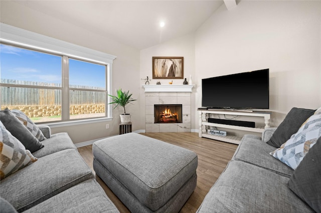 living room featuring hardwood / wood-style flooring, a tiled fireplace, and lofted ceiling