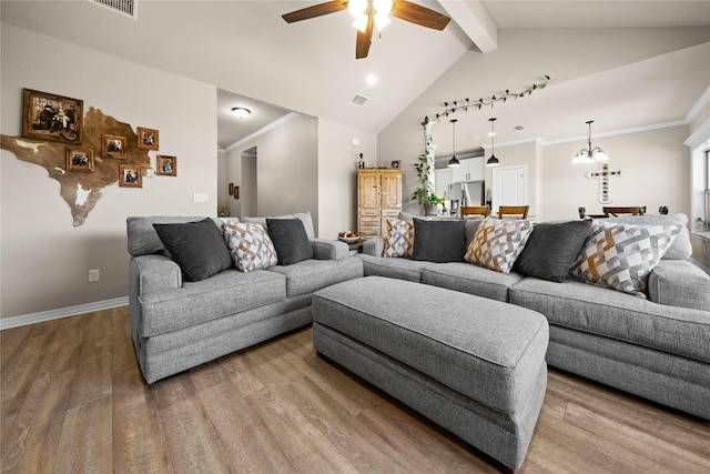 living room featuring hardwood / wood-style flooring, ceiling fan with notable chandelier, vaulted ceiling with beams, and crown molding