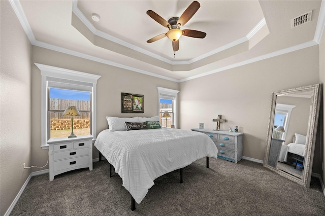 bedroom with ceiling fan, dark carpet, a raised ceiling, and multiple windows