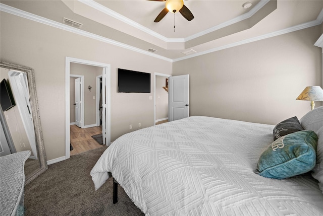 carpeted bedroom with crown molding, ceiling fan, and a raised ceiling