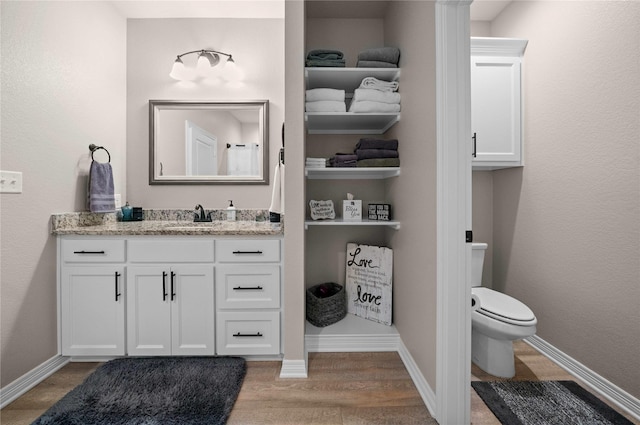 bathroom with wood-type flooring, toilet, and vanity