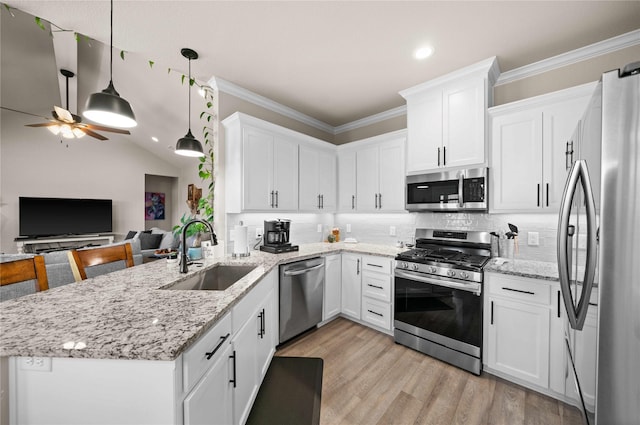 kitchen with kitchen peninsula, pendant lighting, sink, white cabinetry, and stainless steel appliances