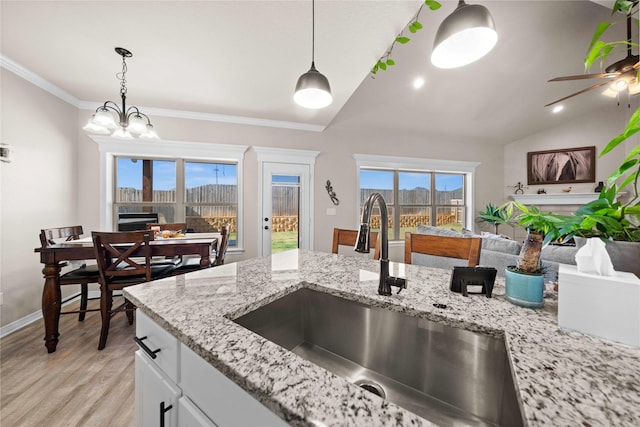 kitchen with sink, white cabinets, lofted ceiling, and hanging light fixtures