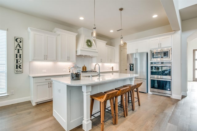 kitchen with white cabinets, stainless steel appliances, a kitchen island with sink, and a breakfast bar area