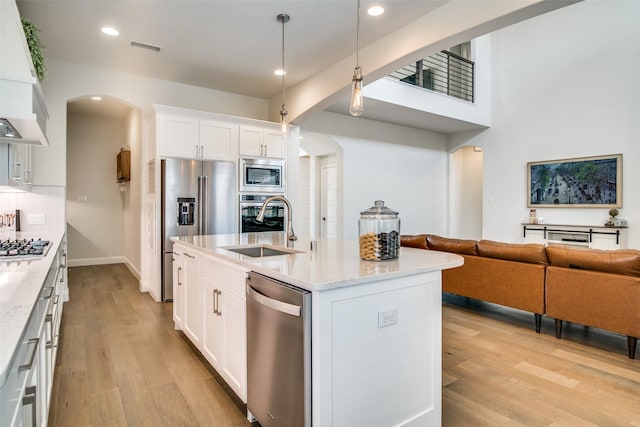 kitchen featuring decorative light fixtures, premium range hood, white cabinetry, light stone countertops, and stainless steel appliances