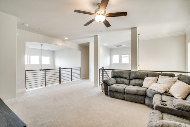 living room with ceiling fan, light colored carpet, ornamental molding, and plenty of natural light