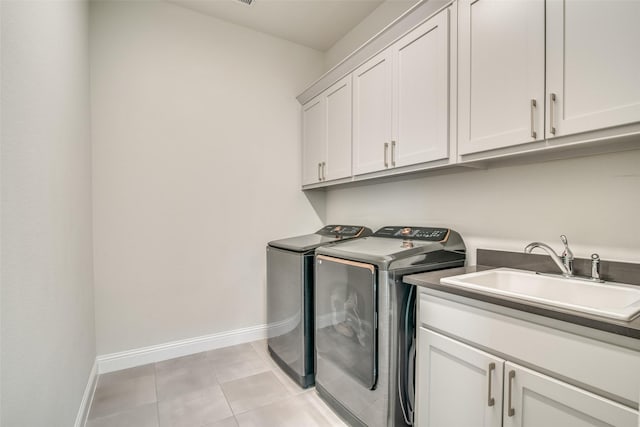 washroom with sink, cabinets, light tile patterned floors, and washing machine and clothes dryer