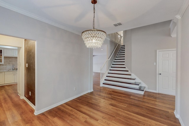 interior space with light hardwood / wood-style floors, sink, crown molding, and an inviting chandelier