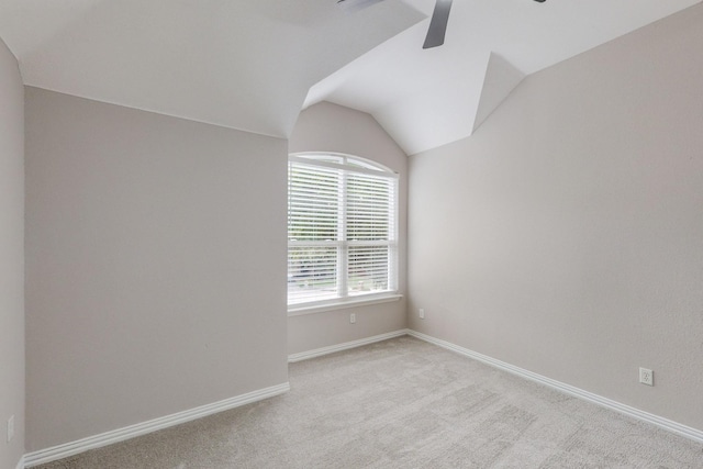 empty room featuring light carpet, vaulted ceiling, and ceiling fan