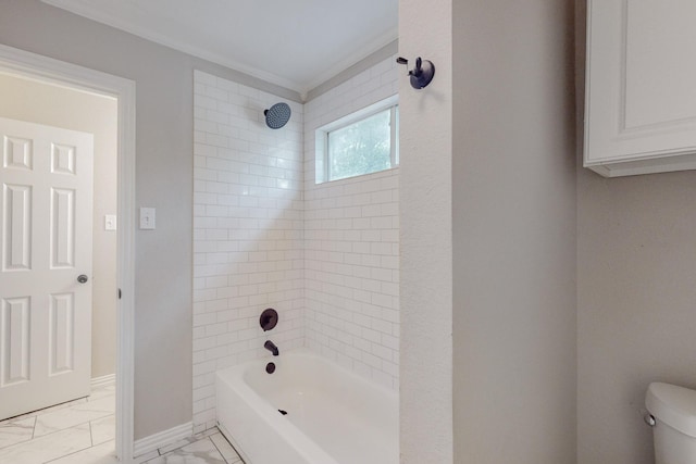 bathroom with toilet, ornamental molding, and tiled shower / bath combo