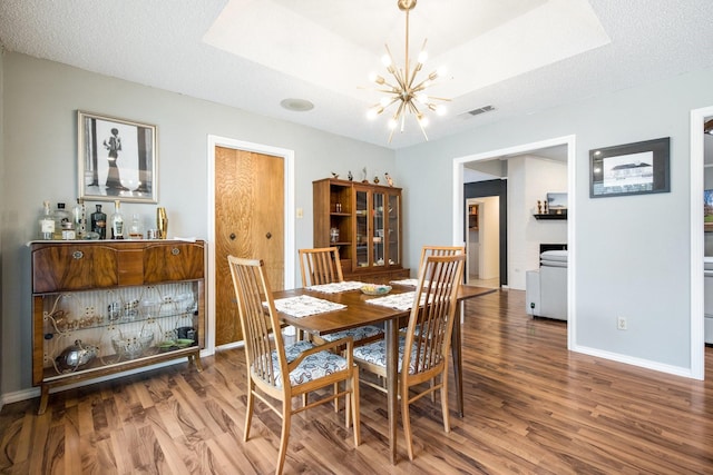 dining space featuring a notable chandelier, a tray ceiling, and wood-type flooring