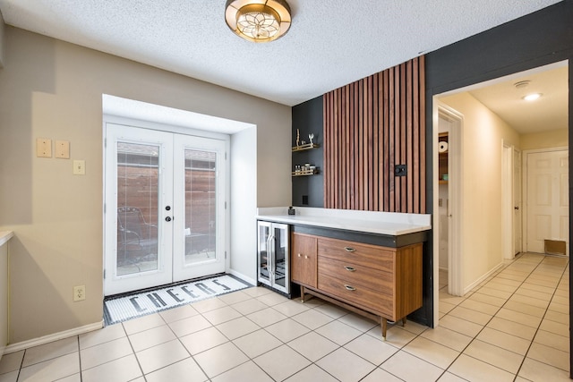 interior space with wine cooler, light tile patterned floors, french doors, and a textured ceiling