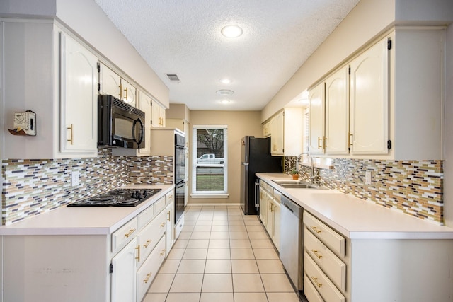 kitchen with sink, light tile patterned floors, backsplash, black appliances, and a textured ceiling