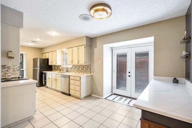 kitchen with appliances with stainless steel finishes, sink, decorative backsplash, light tile patterned floors, and french doors