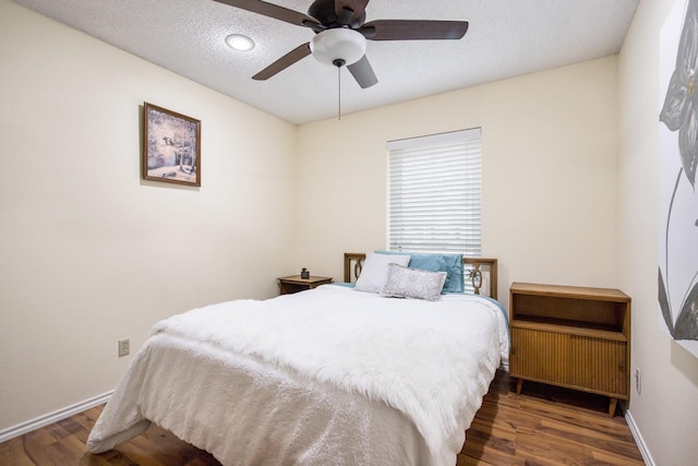 bedroom with ceiling fan, dark wood-type flooring, and a textured ceiling