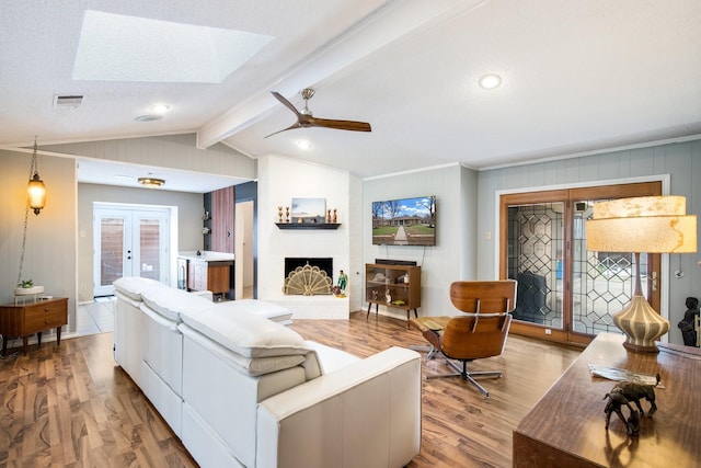 living room featuring a fireplace, lofted ceiling with beams, french doors, ceiling fan, and light hardwood / wood-style flooring