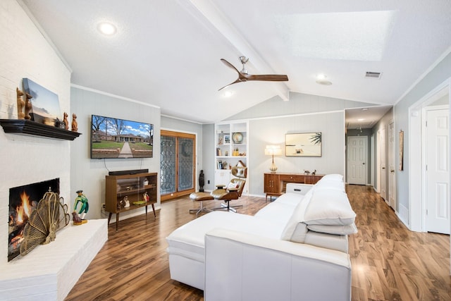 living room with hardwood / wood-style flooring, built in features, ceiling fan, a fireplace, and lofted ceiling with beams