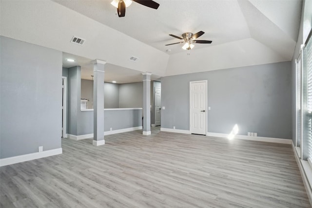 unfurnished living room with lofted ceiling, light hardwood / wood-style floors, ceiling fan, a raised ceiling, and decorative columns