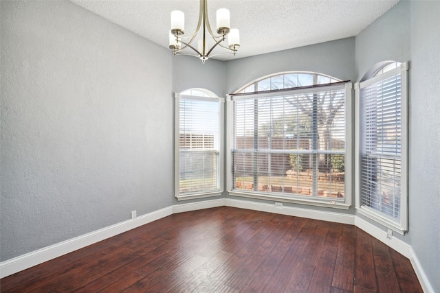 unfurnished room with hardwood / wood-style flooring, a textured ceiling, and a chandelier