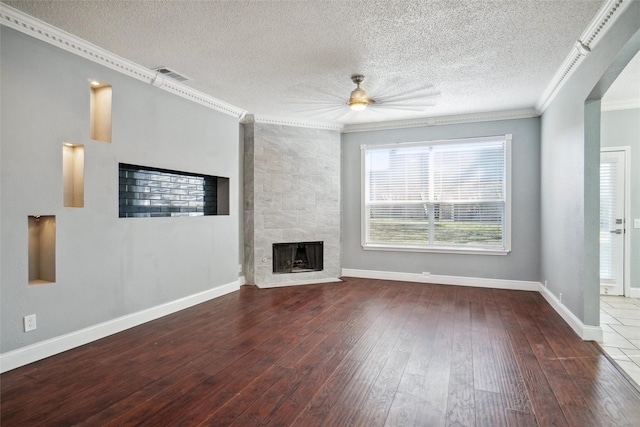 unfurnished living room featuring hardwood / wood-style flooring, ornamental molding, ceiling fan, and a fireplace