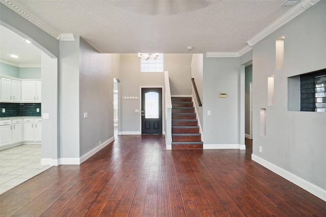 entrance foyer featuring crown molding, hardwood / wood-style flooring, a textured ceiling, and a notable chandelier