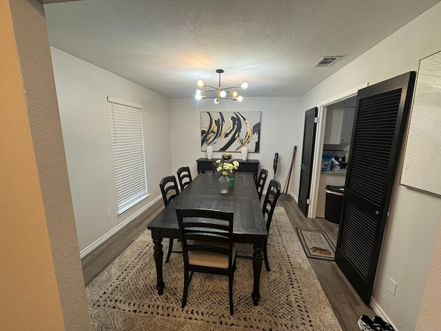 dining room featuring wood-type flooring, an inviting chandelier, and a textured ceiling