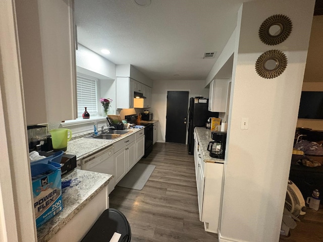 kitchen featuring sink, hardwood / wood-style flooring, white cabinets, light stone countertops, and black appliances