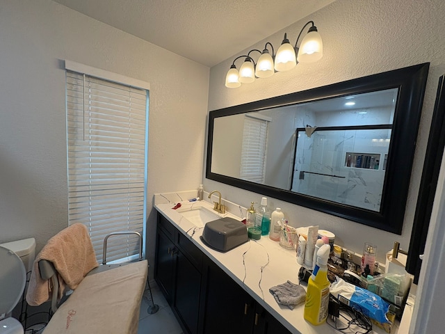 bathroom with a textured ceiling, toilet, walk in shower, and vanity