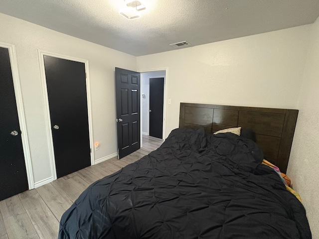 bedroom featuring light wood-type flooring and a textured ceiling