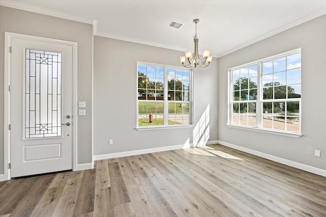 foyer with hardwood / wood-style flooring, ornamental molding, and a chandelier