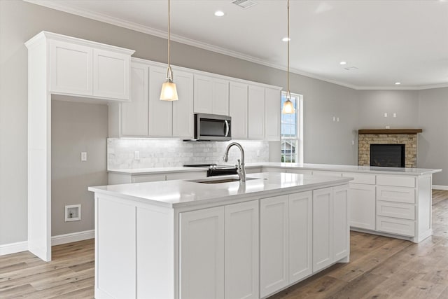 kitchen featuring a kitchen island with sink, sink, pendant lighting, and white cabinetry