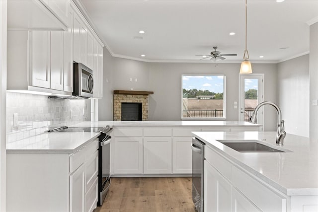 kitchen with white cabinetry, appliances with stainless steel finishes, decorative light fixtures, and sink