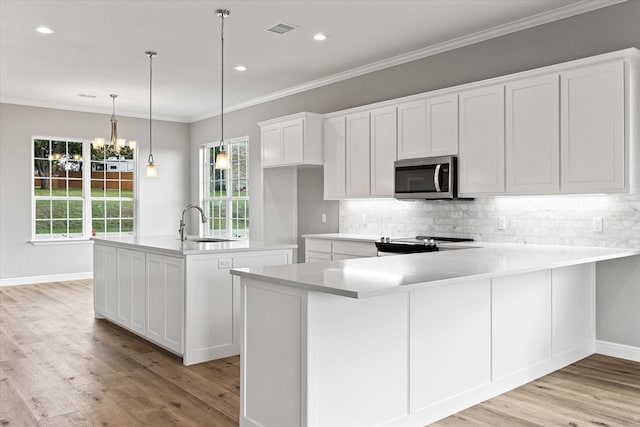 kitchen featuring white cabinetry, stainless steel appliances, an island with sink, decorative backsplash, and decorative light fixtures