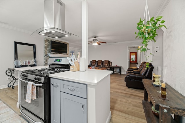 kitchen with gas range, ornamental molding, gray cabinets, island exhaust hood, and light hardwood / wood-style floors