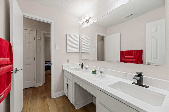 bathroom featuring hardwood / wood-style flooring, vanity, and a textured ceiling