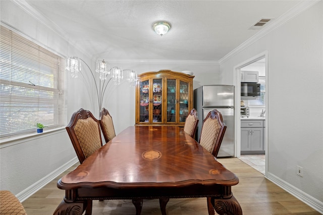 dining room featuring ornamental molding and light wood-type flooring