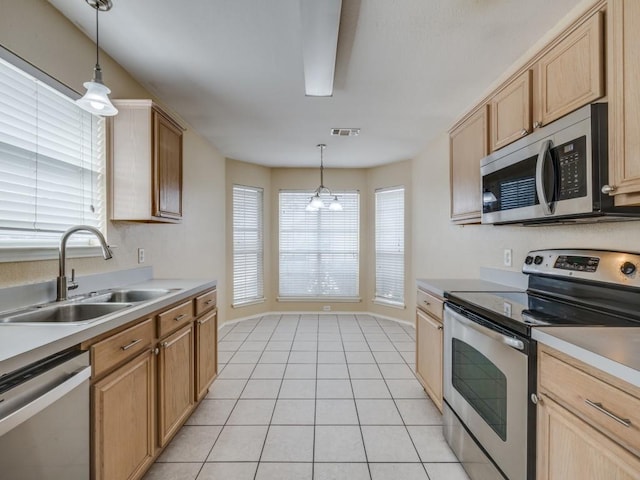 kitchen featuring sink, stainless steel appliances, light tile patterned floors, and decorative light fixtures