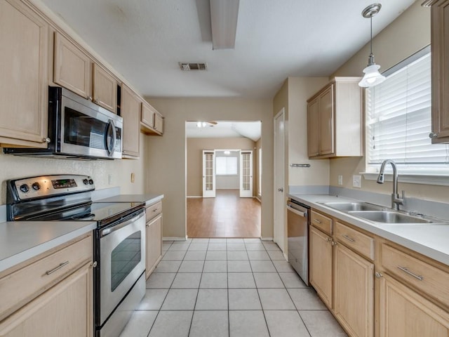 kitchen with sink, stainless steel appliances, hanging light fixtures, and light brown cabinets